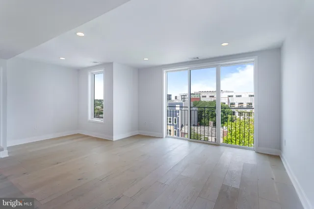 an empty room with wooden floor and natural light