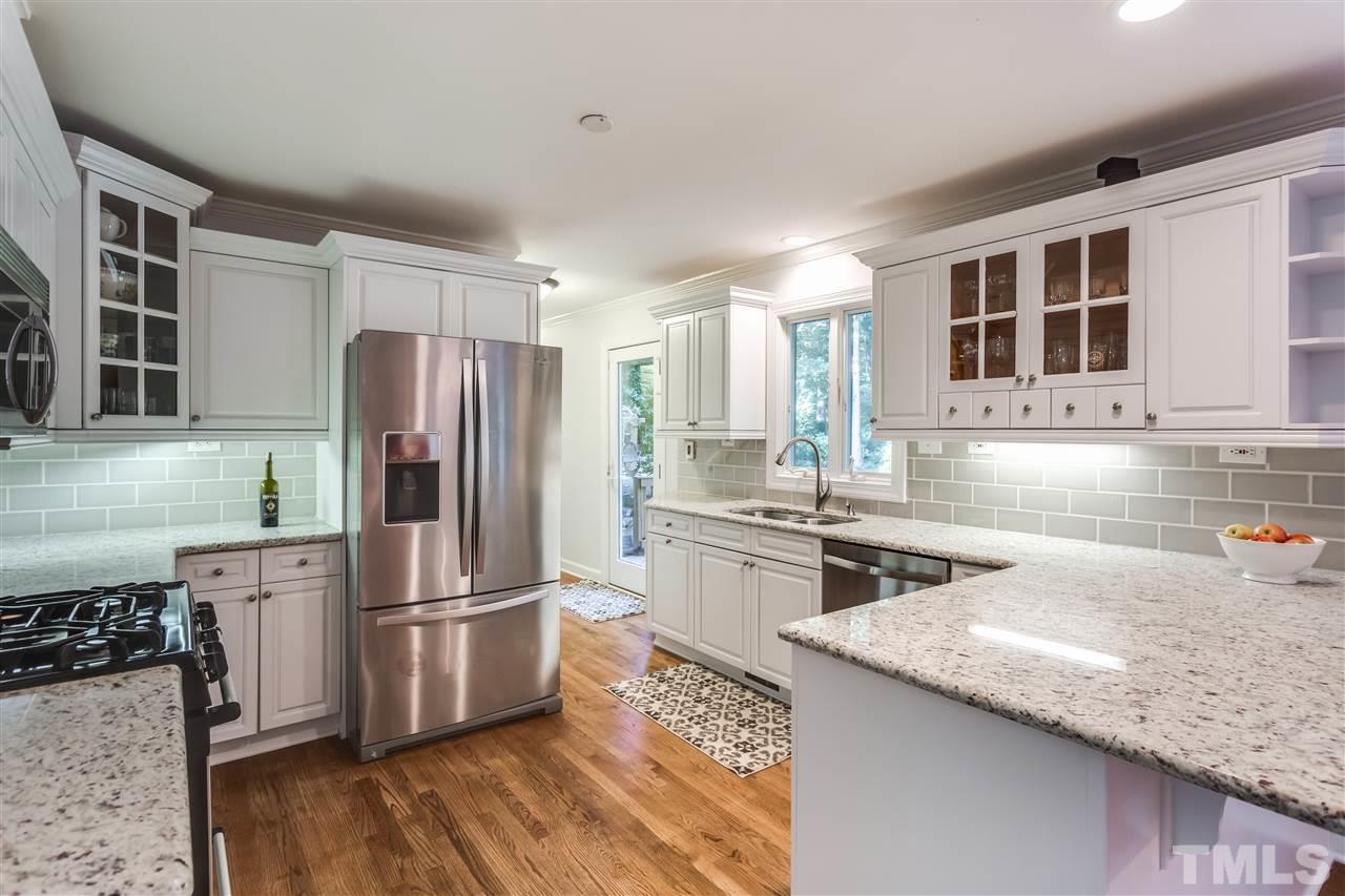 8713 Cliff Top Court Raleigh, NC 27613 - Photo 6 of 25 a kitchen with granite countertop a refrigerator a sink dishwasher and wooden cabinets with wooden floor
