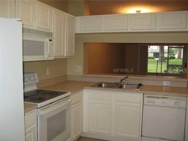 a kitchen with granite countertop white cabinets and white appliances