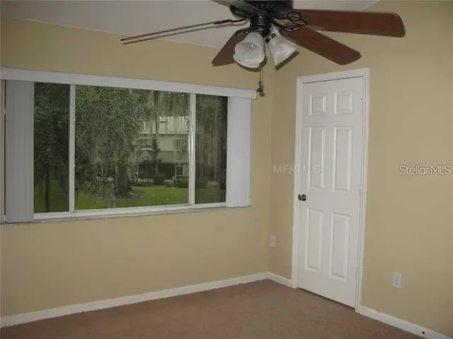 a view of a room that has a large window a chandelier and front door