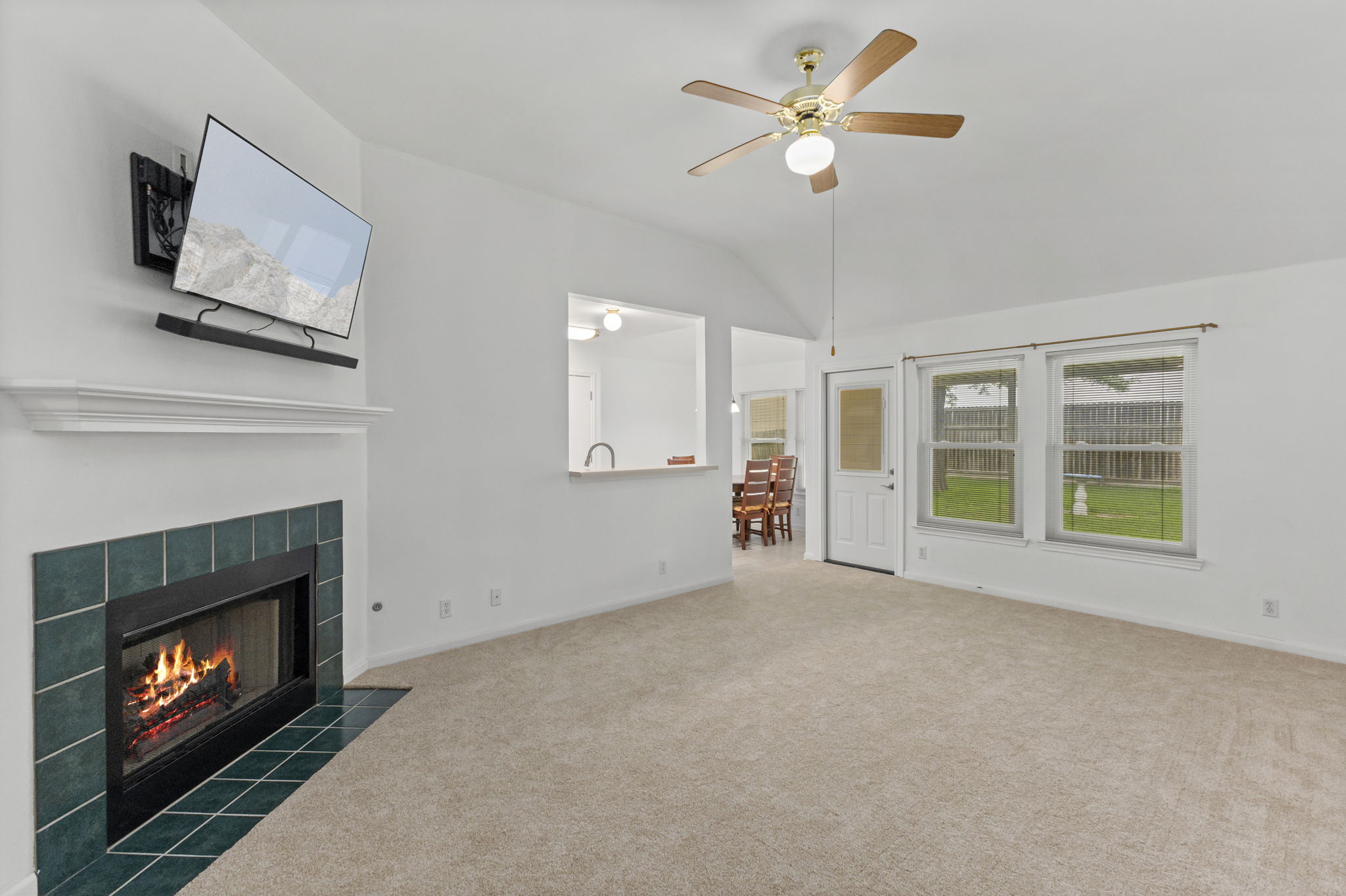 290 Bailey Loop Kyle, TX 78640 - Photo 11 of 33 Living area featuring a fireplace with teal tile surround, vaulted ceiling, and ceiling fan