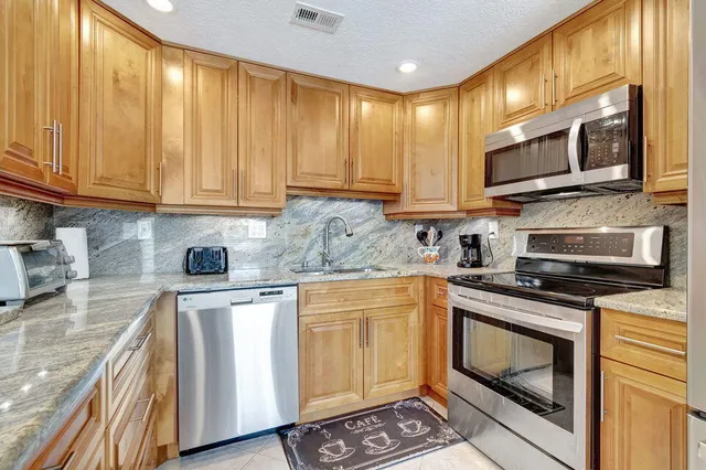 a kitchen with stainless steel appliances granite countertop a stove a sink and a microwave
