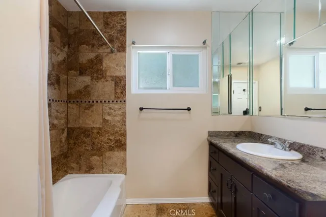 a bathroom with a granite countertop sink a mirror and a bathtub