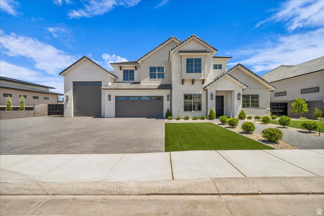 1620 Belayer Drive St. George, UT 84770 - Photo 1 of 51 Modern farmhouse exterior featuring light-colored brick and vertical siding, a multi-car garage, manicured artificial turf, and a paved driveway