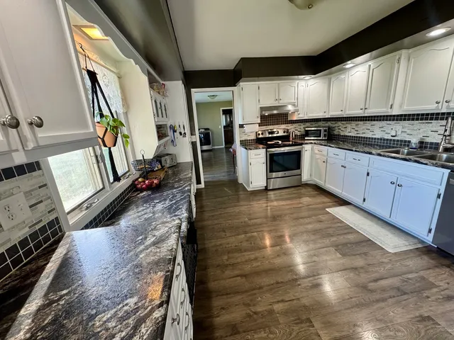 a kitchen with stainless steel appliances granite countertop a stove a sink and a microwave