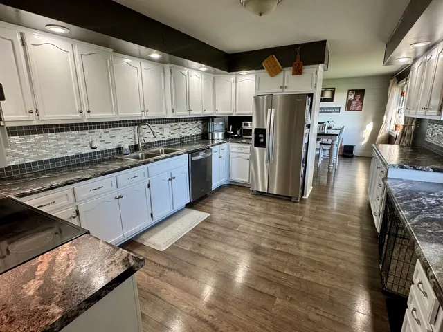 a kitchen with stainless steel appliances granite countertop a sink a stove and a refrigerator