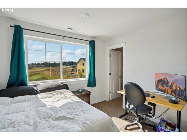 a bedroom with a bed a desk and chair with window