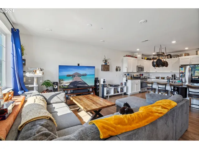 a living room with furniture kitchen view and a large window