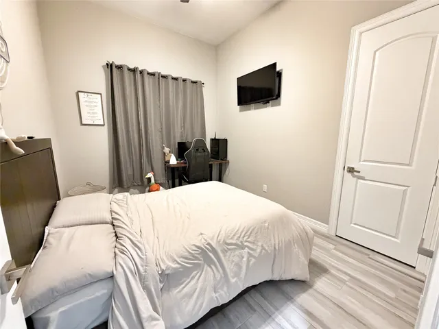 a bedroom with a bed a flat screen tv and a mirror