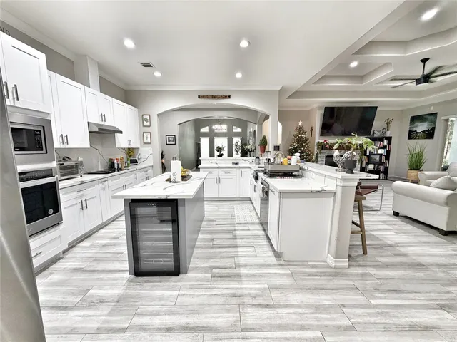 a large white kitchen with kitchen island a stove a sink dishwasher and white cabinets with wooden floor