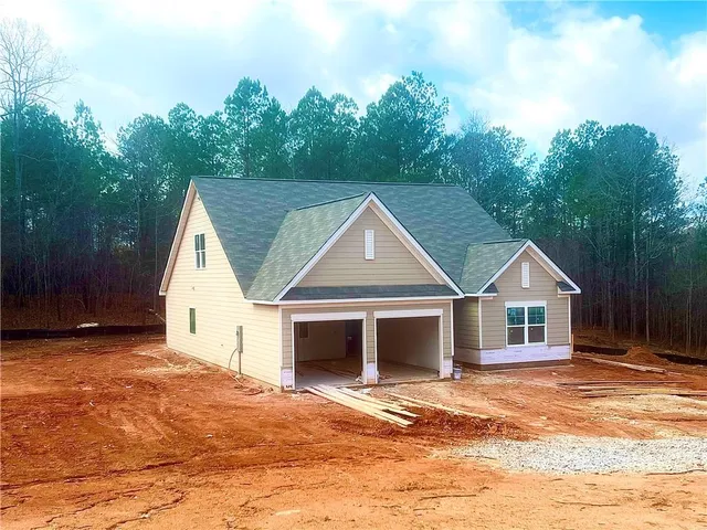 a front view of a house with a garden and trees