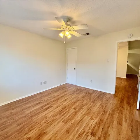 a view of a room with wooden floor and a ceiling fan