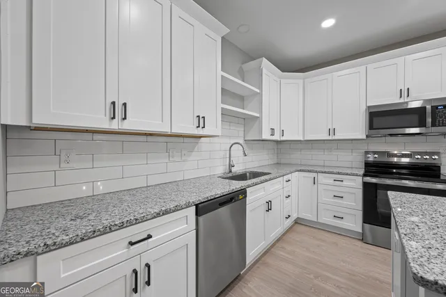 a kitchen with granite countertop white cabinets and stainless steel appliances