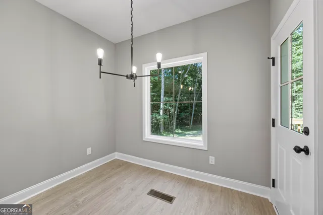 a view of an empty room with wooden floor closet and a window