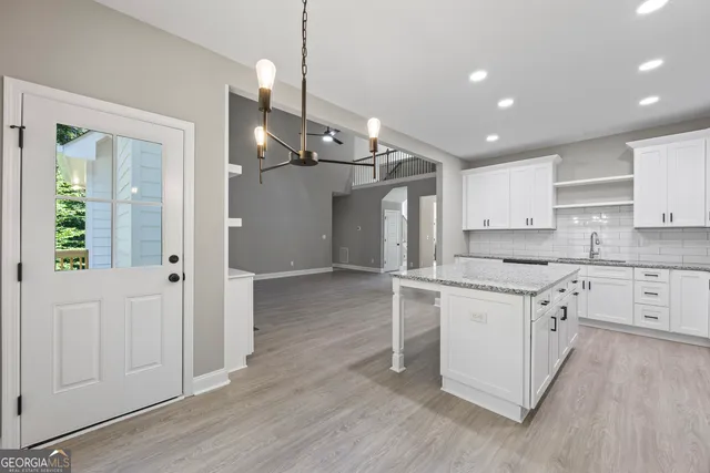 a kitchen with stainless steel appliances granite countertop a refrigerator a sink dishwasher a stove and white cabinets with wooden floor