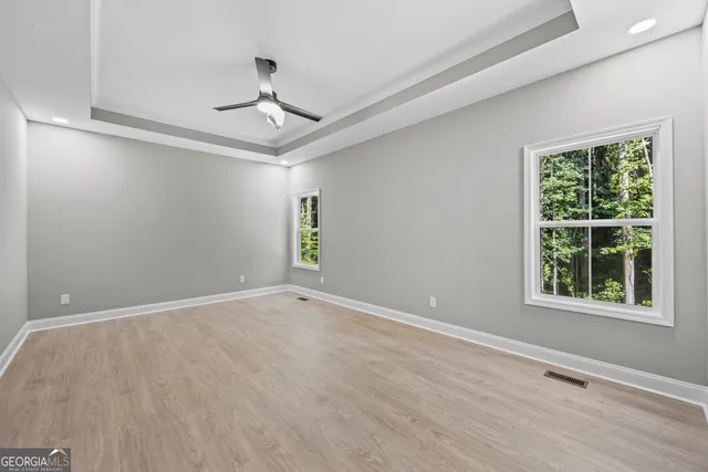 a view of an empty room with wooden floor and windows
