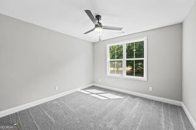 an empty room with a window and ceiling fan