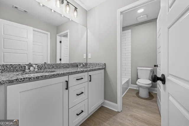 a bathroom with a granite countertop toilet sink and mirror