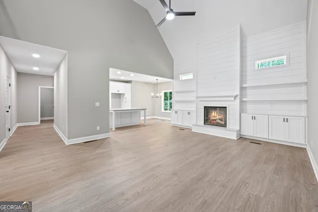 an empty room with wooden floor fireplace and windows