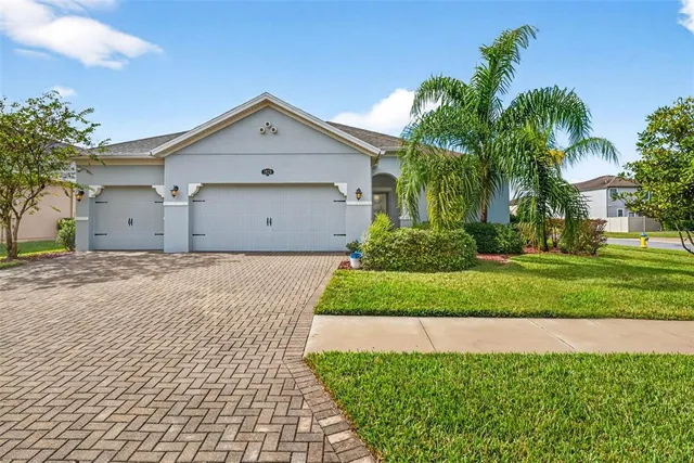 a view of a white house with a yard and potted plants