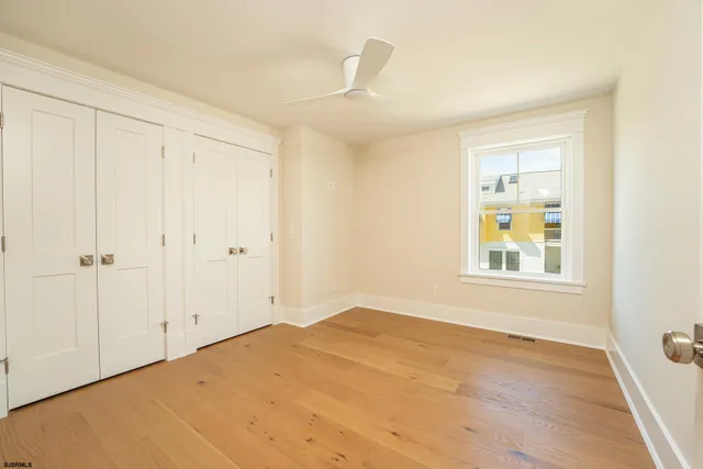 a view of empty room with wooden floor and fan