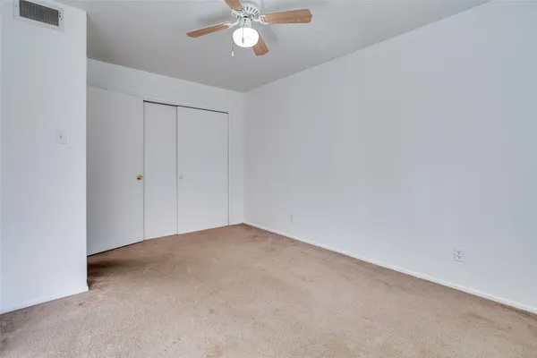 a view of an empty room with a chandelier fan