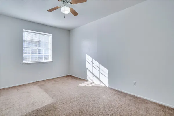 an empty room with a window and a ceiling fan