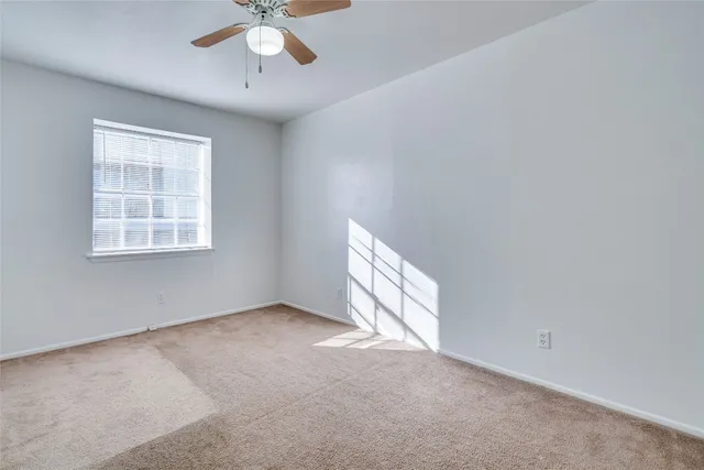 an empty room with a window and a ceiling fan