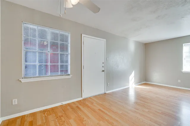 an empty room with wooden floor and windows