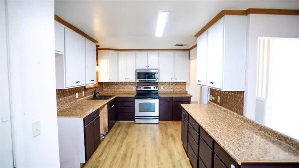 a kitchen with stainless steel appliances granite countertop a stove a sink and a microwave