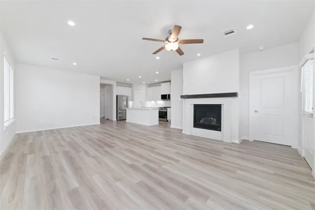 a view of an empty room with wooden floor fireplace and a window