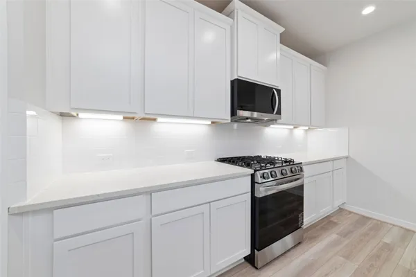 a kitchen with white cabinets and appliances