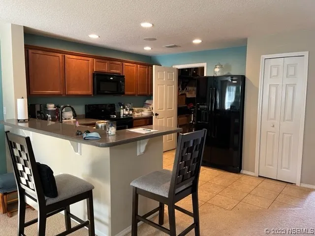 a kitchen with stainless steel appliances granite countertop a table chairs and a refrigerator