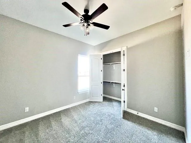 an empty room with a ceiling fan and window