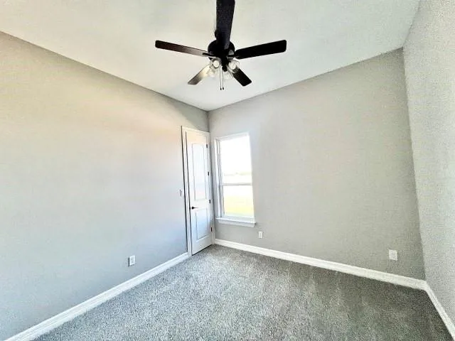 an empty room with windows and ceiling fan