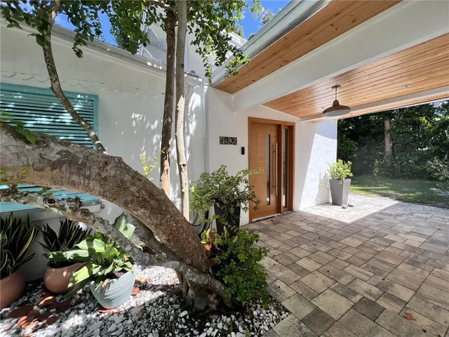 a front view of a house with a yard and potted plants