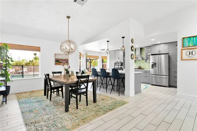 a view of a dining room and livingroom with furniture large windows a rug and a chandelier