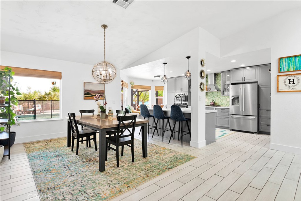 37077 Coyote Lake Road Newberry Springs, CA 92365 - Photo 11 of 58 a view of a dining room and livingroom with furniture large windows a rug and a chandelier