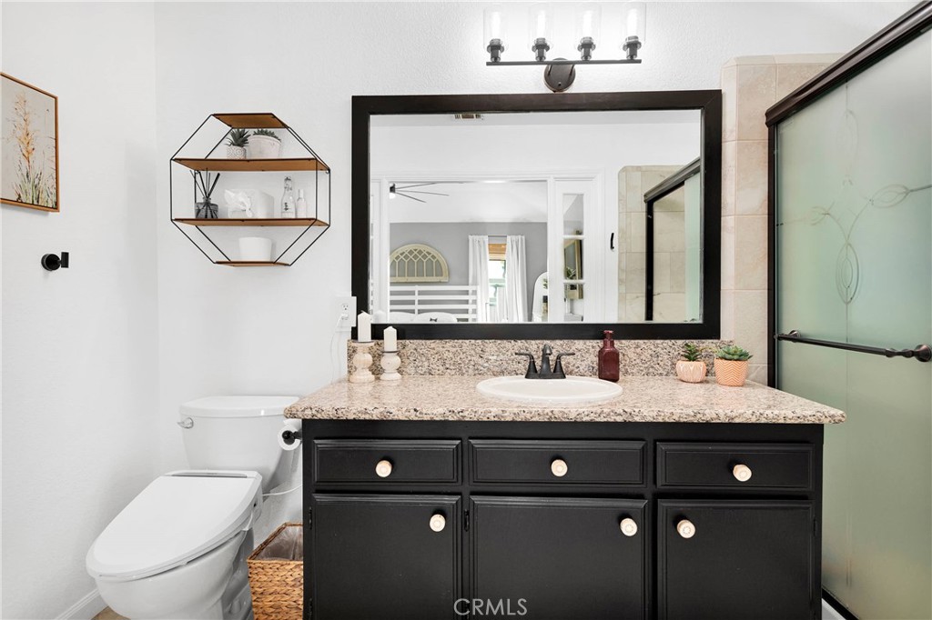 37077 Coyote Lake Road Newberry Springs, CA 92365 - Photo 27 of 58 a bathroom with a granite countertop sink a toilet and a mirror