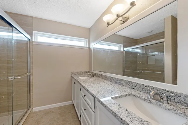 a bathroom with a granite countertop sink a mirror and shower