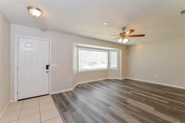 an empty room with windows and chandelier fan