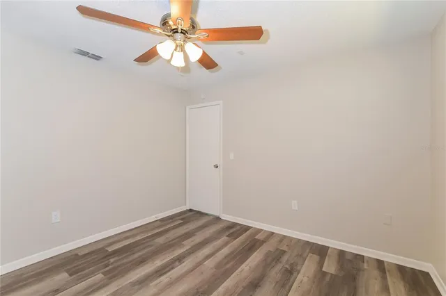 an empty room with a fan & a ceiling fan