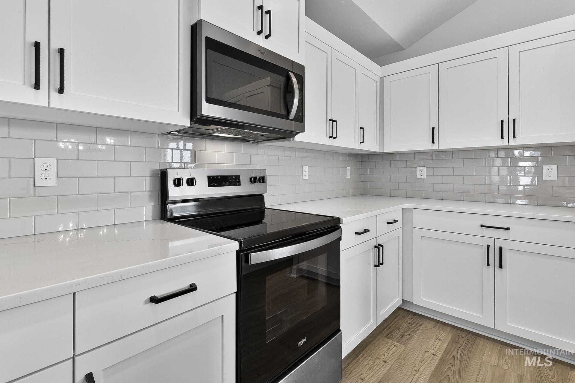 1164 Velvet Loop Wilder, ID 83676 - Photo 11 of 35 Kitchen with stainless steel appliances, white cabinets, light stone countertops, backsplash, and light wood finished floors