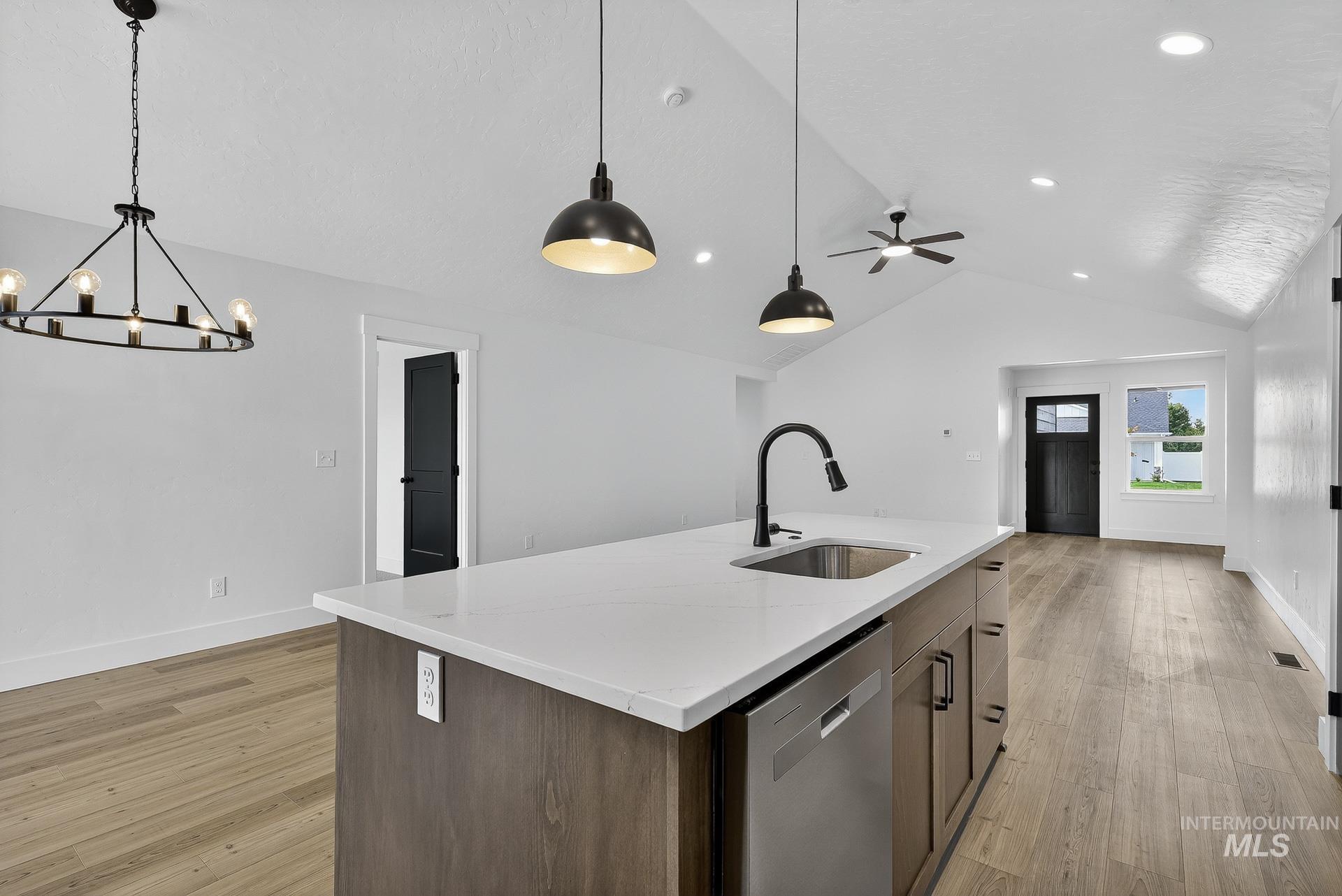 1164 Velvet Loop Wilder, ID 83676 - Photo 13 of 35 Kitchen featuring stainless steel dishwasher, light wood-type flooring, a center island with sink, light stone counters, and hanging light fixtures