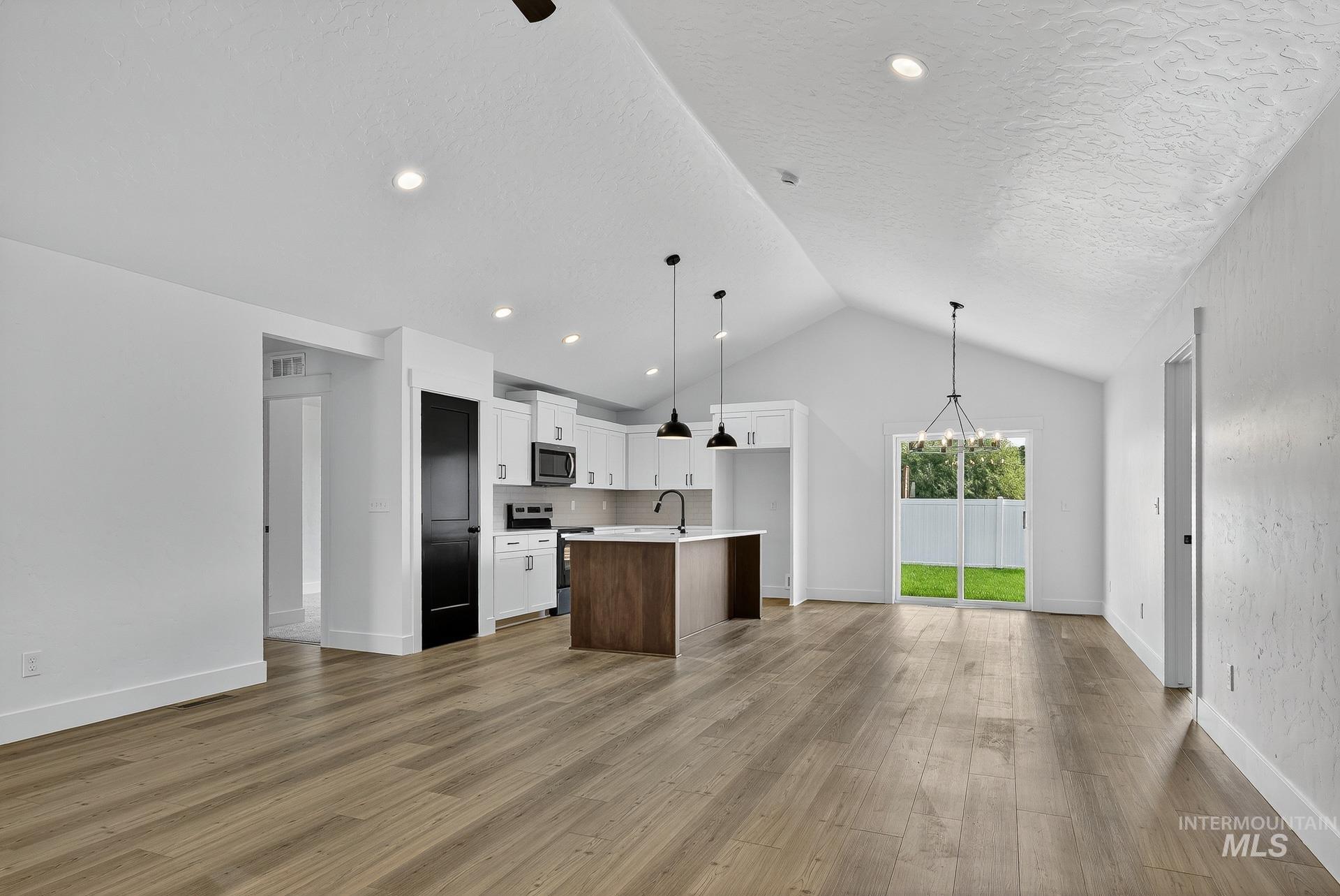 1164 Velvet Loop Wilder, ID 83676 - Photo 35 of 35 Kitchen with open floor plan, white cabinets, appliances with stainless steel finishes, hanging light fixtures, and a kitchen island with sink