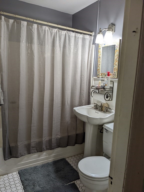 73-75 Sylvan Street Springfield, MA 01108 - Photo 7 of 15 a bathroom with a sink a mirror a toilet and shower curtain