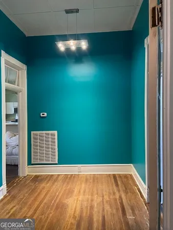 a view of an empty room with window and chandelier fan