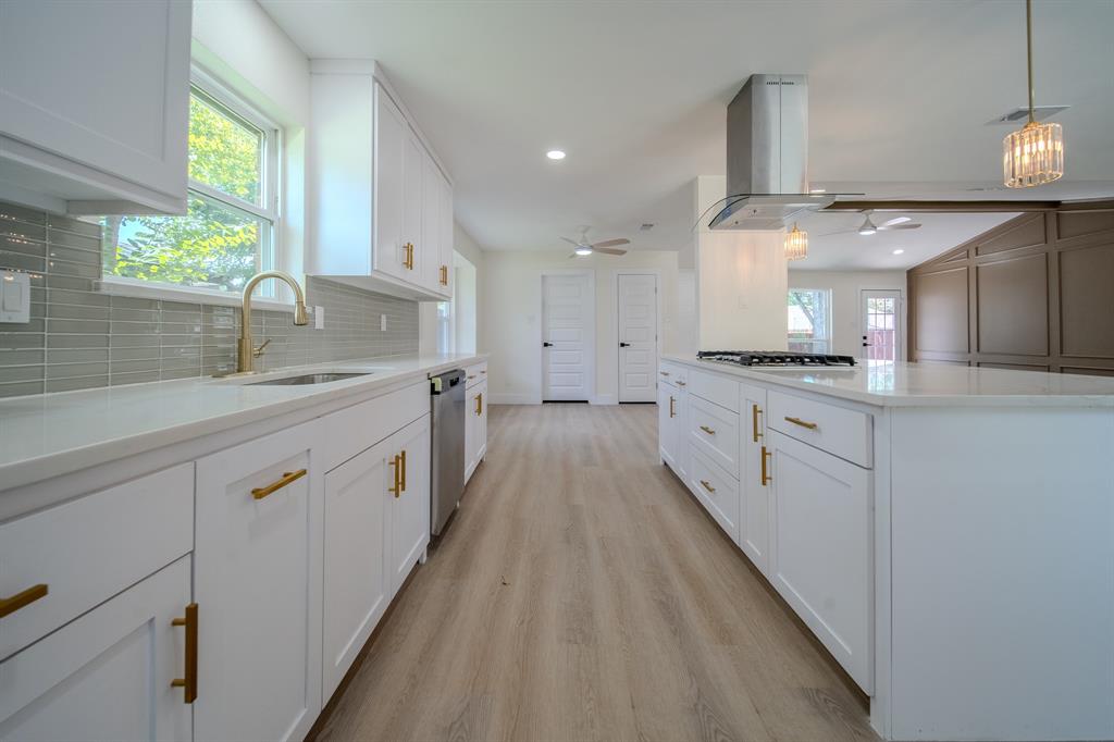 142 Ridgegate Drive Garland, TX 75040 - Photo 14 of 26 Modern kitchen featuring white cabinetry, quartz countertops, a gray tile backsplash, stainless steel appliances, and wood-finish flooring