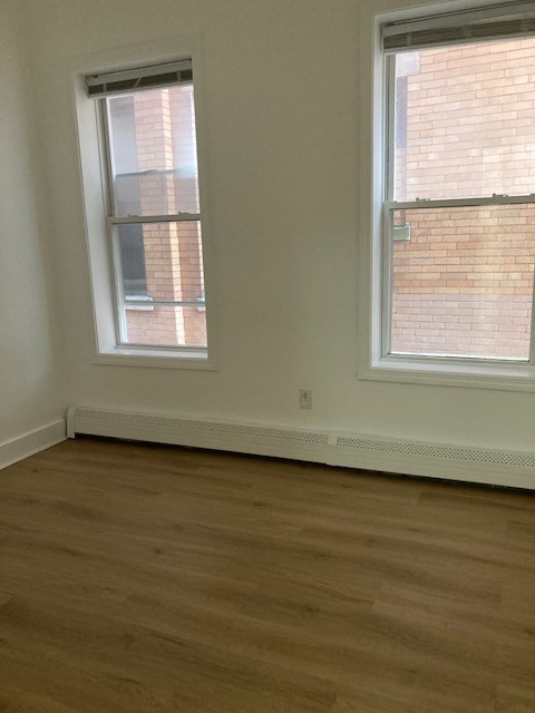 675 Washington Street, Unit 1 Brookline, MA 02446 - Photo 9 of 16 an empty room with wooden floor and windows