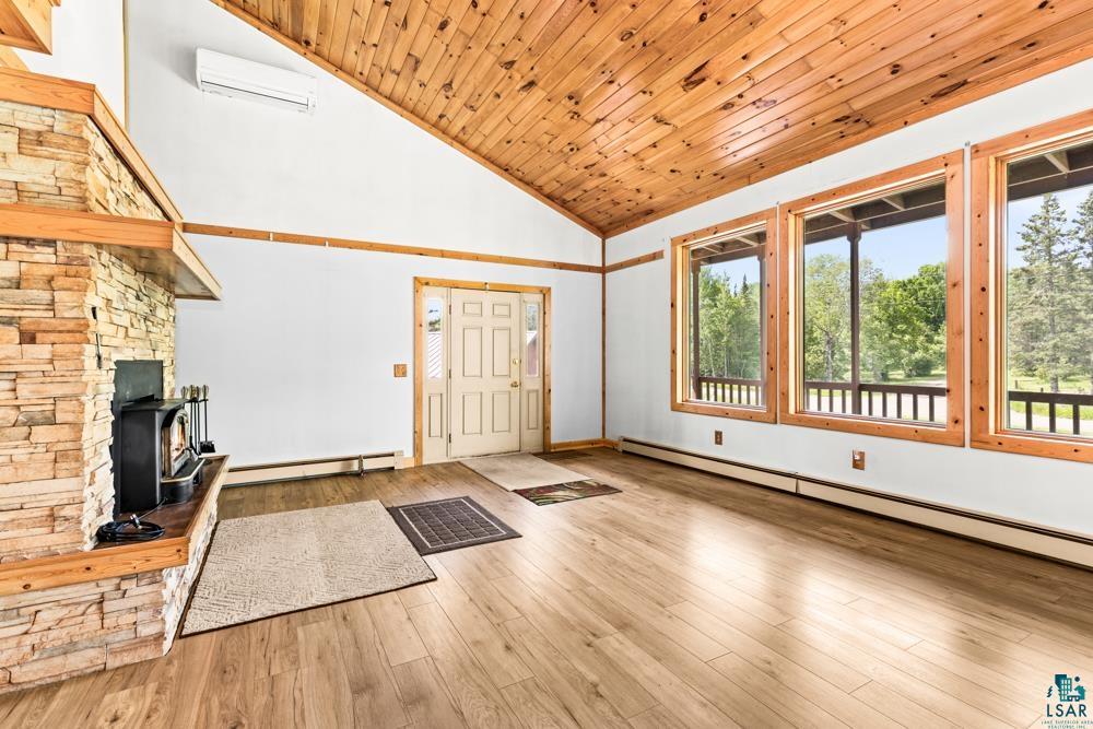 740 Seboe Road Wrenshall, MN 55797 - Photo 7 of 20 Unfurnished living room featuring high vaulted ceiling, a wood stove, a baseboard heating unit, and hardwood / wood-style floors